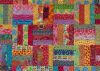 A colorful patchwork quilt with various vibrant fabrics in patterns like florals, dots, and geometric shapes, all stitched together with visible quilting lines.