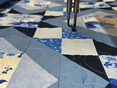 Longarm quilting services performed on a beautiful blue, navy, light blue floral flowers quilt.